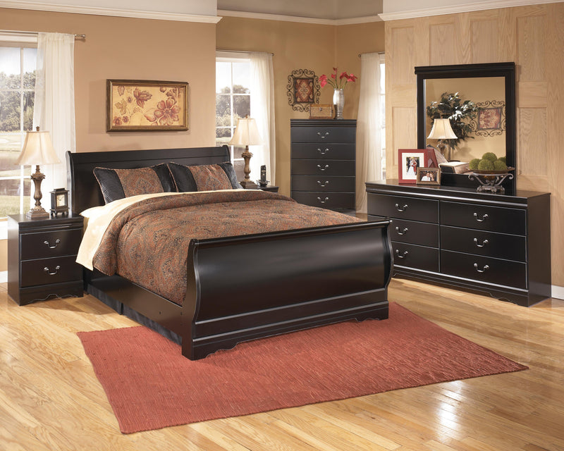 Ashley Furniture Huey Vineyard Bed with a wooden frame and upholstered headboard, shown in a cozy bedroom setting.