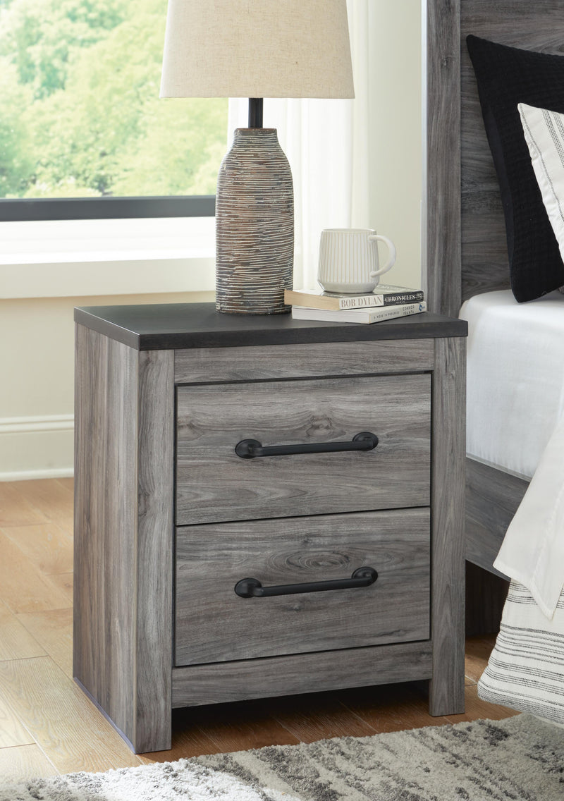 Ashley Furniture Bronyan nightstand with a dark wood finish and modern design, featuring a single drawer and open shelf.