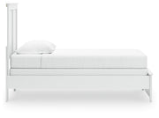 Ashley Furniture Bostwick Shoals Bed with a wooden frame and headboard, shown from a side angle in a well-lit bedroom setting.