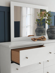 Ashley Furniture Bostwick Shoals dresser with matching mirror showing a wood finish and sleek handles in a modern bedroom setting.