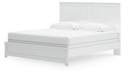 Ashley Furniture Bostwick Shoals bed with a wooden frame and headboard, shown from an angled perspective in a bedroom setting.