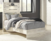 Ashley Furniture Cambeck Bed with a wooden frame and detailed headboard, shown in a cozy bedroom setting.
