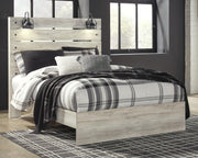 Ashley Furniture Cambeck Bed with a wooden frame and detailed headboard, shown in a cozy bedroom setting.