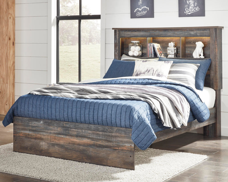 Ashley Furniture Drystan Youth Bed with a wooden frame and storage drawers, shown in a cozy bedroom setting.