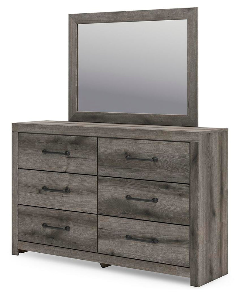 Ashley Furniture Graystorm bedroom set showing a gray upholstered bed, matching nightstands, and dresser in a modern bedroom scene.
