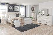 Ashley Furniture Stelsie Bed with a wooden frame and plush fabric upholstery, shown in a cozy bedroom setting.