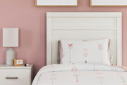 Ashley Furniture Stelsie Bed with upholstered headboard and wooden frame, shown in a cozy bedroom setting.