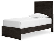 Ashley Furniture Belachime bed with a wooden frame, detailed headboard, and neutral finish, shown from an angled side view.