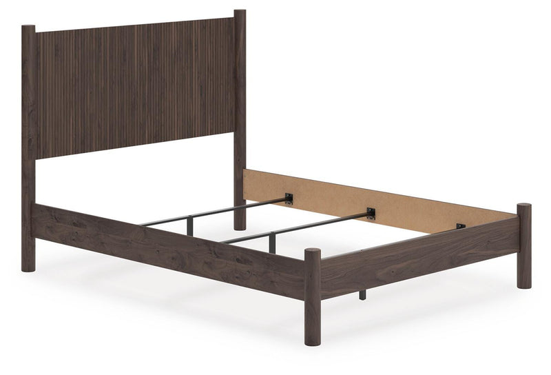 Ashley Furniture Pamytta Bed with beige upholstered headboard and wooden frame, shown from an angled side view.