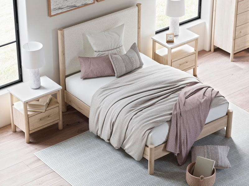 Ashley Furniture Cadmori upholstered bed with a plush fabric headboard and sleek frame, shown in a modern bedroom setting.