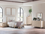 Ashley Furniture Cadmori chest of drawers with a dark wood finish and sleek metal handles, shown in a modern bedroom setting.