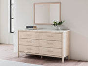 Ashley Furniture Cadmori bedroom mirror, rectangular with beveled glass and wood frame, hangs on a wall in a modern bedroom setting.