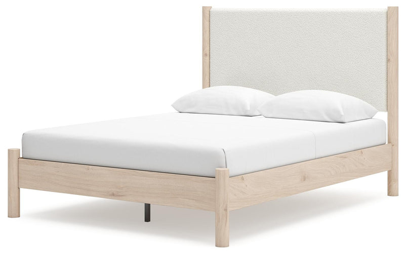 Ashley Furniture Cadmori upholstered bed with a tufted headboard and neutral fabric, shown in an angled view.