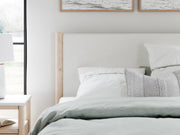 Ashley Furniture Cadmori upholstered bed with tufted headboard and neutral fabric, showcasing detailed fabric and elegant design.