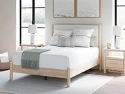 Ashley Furniture Cadmori upholstered bed with plush fabric headboard and sturdy wooden frame, shown in a stylish bedroom setting.