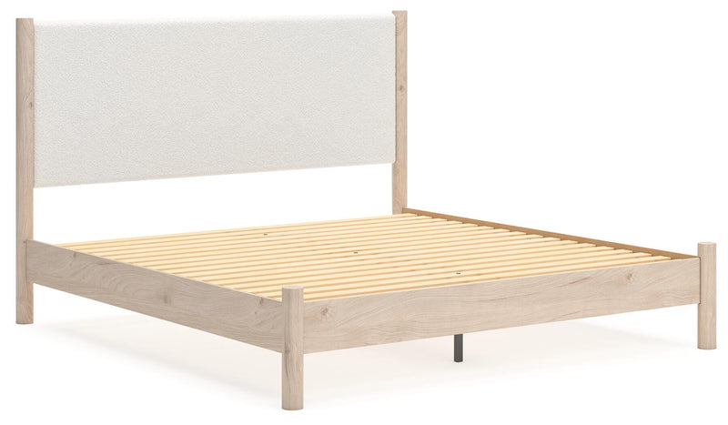 Ashley Furniture Cadmori upholstered bed with a plush headboard and elegant design, shown from an angle in natural lighting.