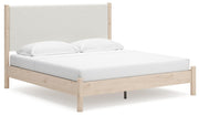 Ashley Furniture Cadmori upholstered bed with a tufted headboard and neutral fabric, shown from a side angle.