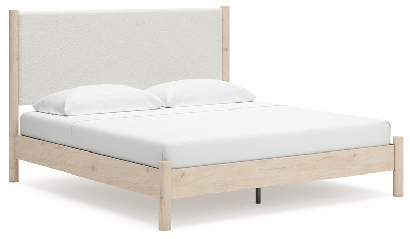 Ashley Furniture Cadmori upholstered bed with a tufted headboard and neutral fabric, shown from a side angle.
