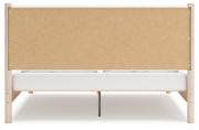 Ashley Furniture Cadmori upholstered bed with a tall, padded headboard and elegant fabric upholstery, shown from the back.