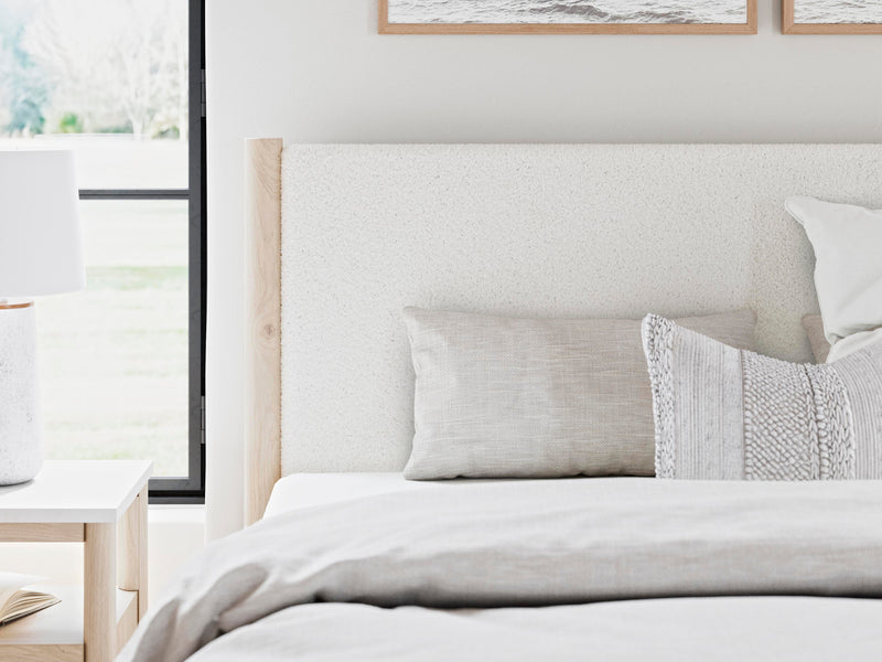 Ashley Furniture Cadmori upholstered bed with detailed fabric headboard in a modern bedroom setting.