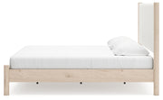 Ashley Furniture Cadmori upholstered bed with a padded headboard and neutral fabric, shown from the side view.