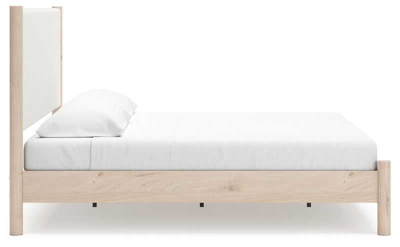 Ashley Furniture Cadmori upholstered bed with a padded headboard and sleek design, shown from the side in a modern bedroom setting.