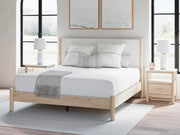 Ashley Furniture Cadmori upholstered bed with a padded headboard and neutral fabric, showcasing a stylish bedroom centerpiece.