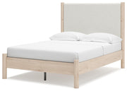 Ashley Furniture Cadmori upholstered bed with a plush, padded headboard and neutral fabric, shown from an angled side view.