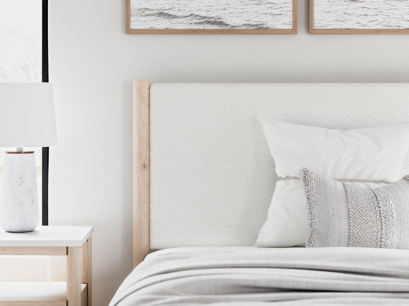 Ashley Furniture Cadmori upholstered bed with tufted headboard and neutral fabric, shown in a detailed close-up.