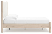 Ashley Furniture Cadmori upholstered bed with beige fabric, padded headboard, and wooden legs, shown from a side angle.