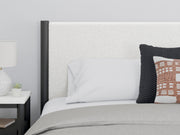 Ashley Furniture Cadmori upholstered bed with detailed fabric headboard and neutral-toned bedding in a cozy bedroom setting.