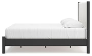 Ashley Furniture Cadmori upholstered bed with tufted headboard and neutral fabric, shown from a side angle.