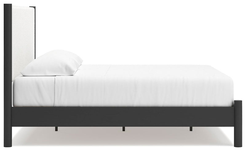 Ashley Furniture Cadmori upholstered bed with a plush, padded headboard and neutral fabric, shown in side view.