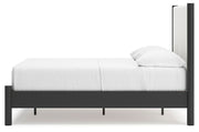 Ashley Furniture Cadmori upholstered bed with a plush headboard and neutral fabric, shown from a side angle.