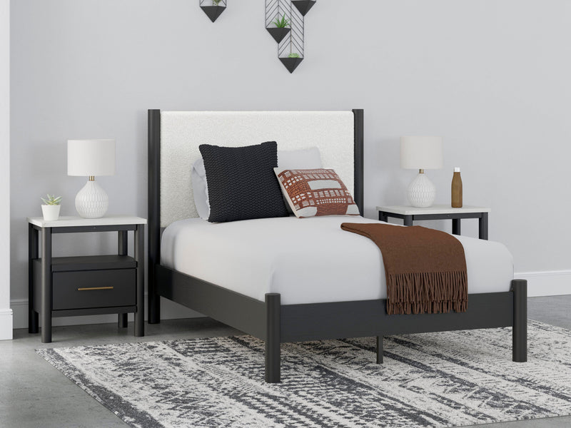 Ashley Furniture Cadmori upholstered bed with a padded headboard and neutral fabric, showcased in a stylish bedroom setting.
