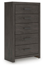 Ashley Furniture Prendonea chest of drawers, angled view showing wood finish and multiple drawer fronts for bedroom storage.