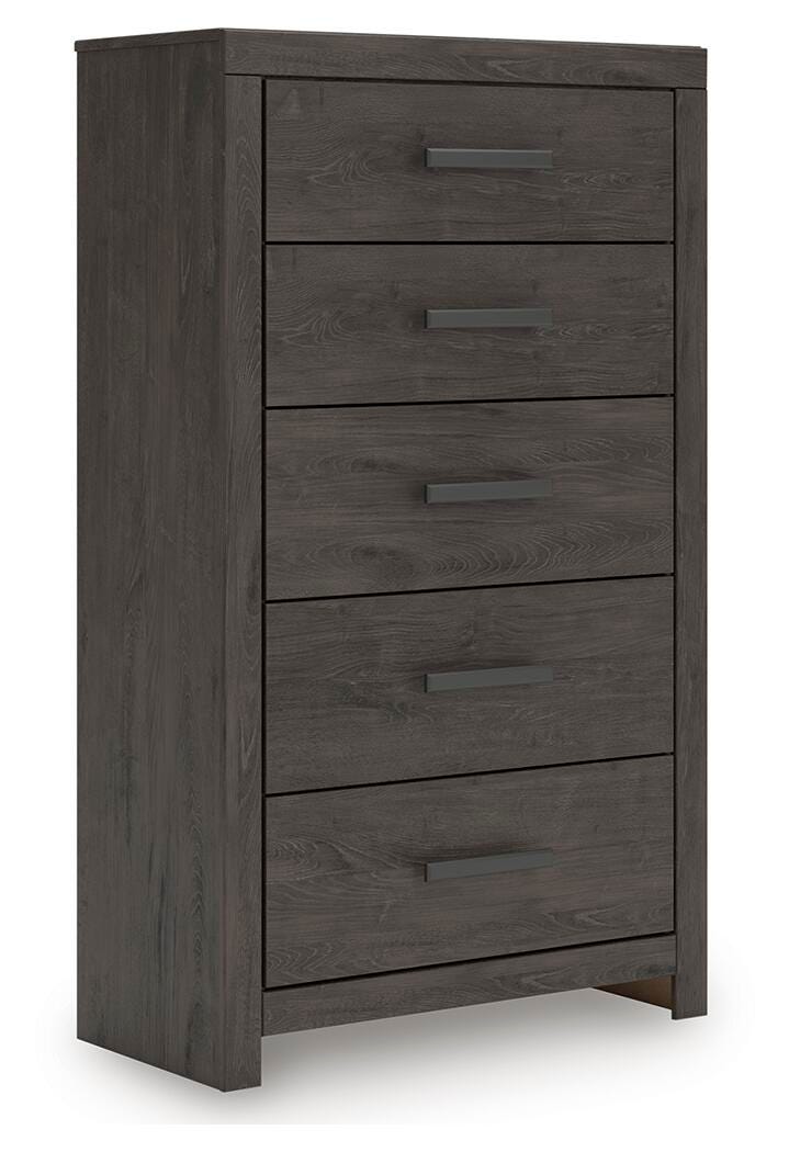 Ashley Furniture Prendonea chest of drawers, angled view showing wood finish and multiple drawer fronts for bedroom storage.