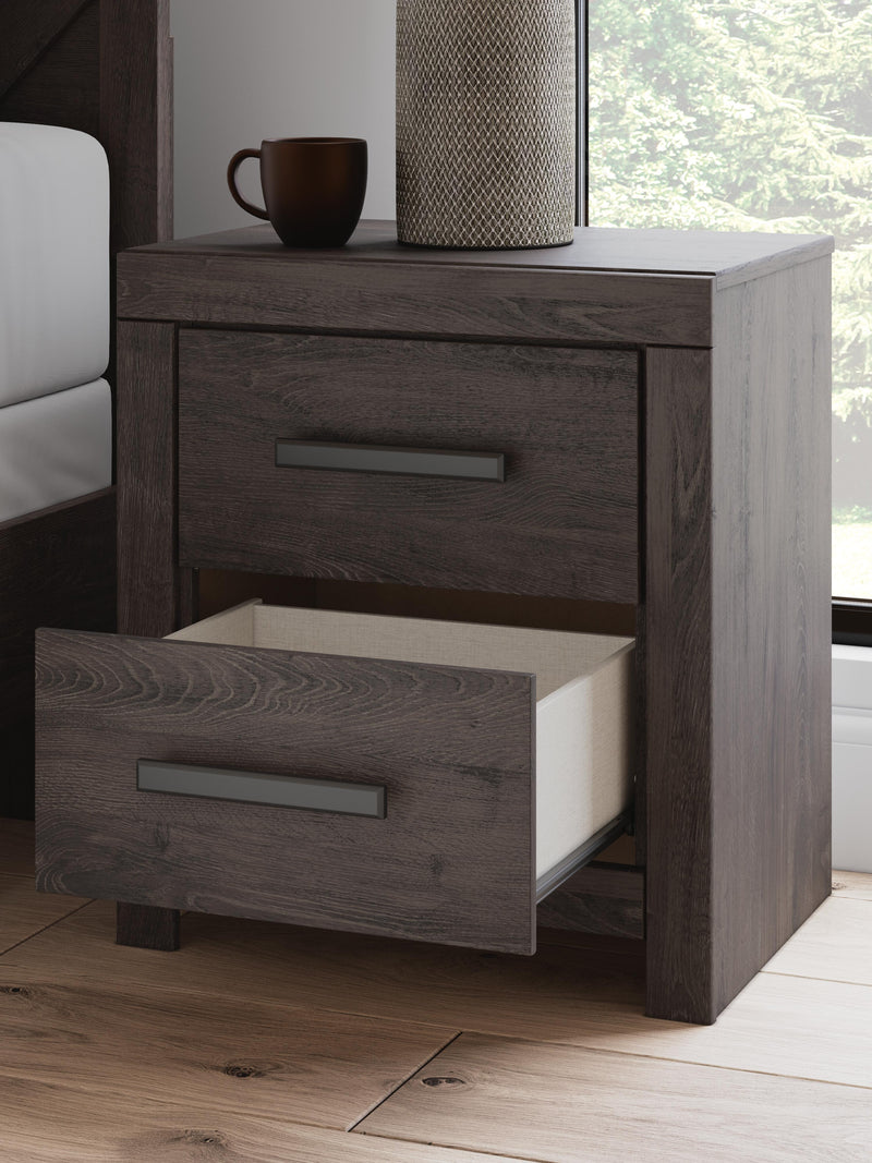 Close-up of Ashley Furniture Prendonea Nightstand with dark wood finish and detailed hardware.
