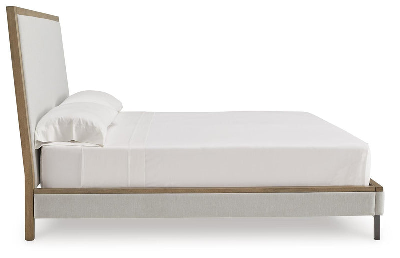 Ashley Furniture Tomtyn upholstered bed with a padded headboard and dark wood finish, shown in a side view.