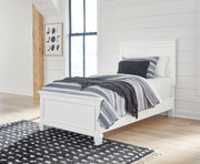 Ashley Furniture Fortman Bed with upholstered headboard and wooden frame, shown in a spacious bedroom setting.
