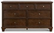 Ashley Furniture Danabrin Dresser with sleek wood finish and multiple drawers, shown head-on in a modern bedroom setting.
