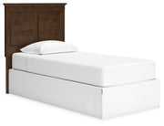 Ashley Furniture Danabrin Panel Storage Bed with angled view, showcasing the wood finish and built-in storage drawers in a modern bedroom setting.