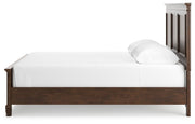 Ashley Furniture Danabrin bed with a wooden frame and upholstered headboard, shown from a side angle.