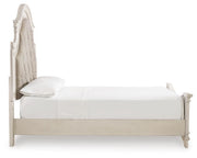 Ashley Furniture Realyn upholstered bed with a padded headboard and neutral fabric, shown from a side view in a well-lit bedroom setting.