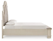 Ashley Furniture Realyn upholstered bed with beige fabric, wooden frame, and tufted headboard, shown from side view.