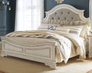 Ashley Furniture Realyn upholstered bed with a plush headboard and neutral fabric, showcasing a modern bedroom setting.