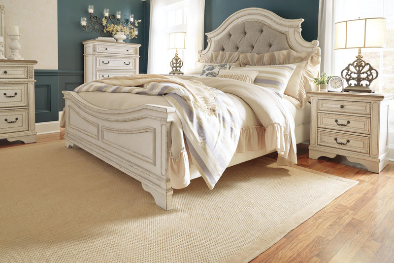 Ashley Furniture Realyn upholstered bed with a padded headboard and neutral fabric, shown in a stylish bedroom setting.