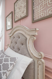 Ashley Furniture Realyn upholstered bed with padded headboard and fabric upholstery, showcasing a stylish bedroom centerpiece.
