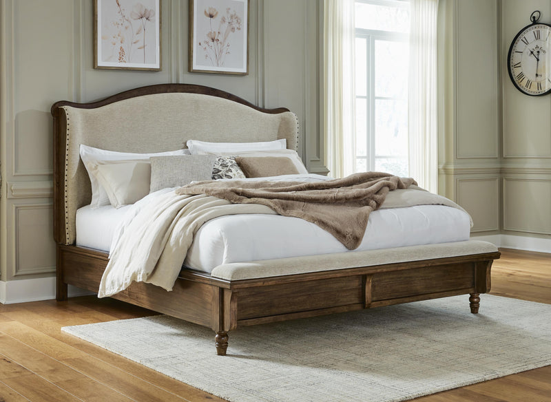 Ashley Furniture Sturlayne upholstered bed with a padded headboard and neutral fabric, showcasing a stylish bedroom centerpiece.