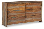 Ashley Furniture Dressonni Dresser with a sleek wood finish, featuring multiple drawers and modern design, shown from an angled view.